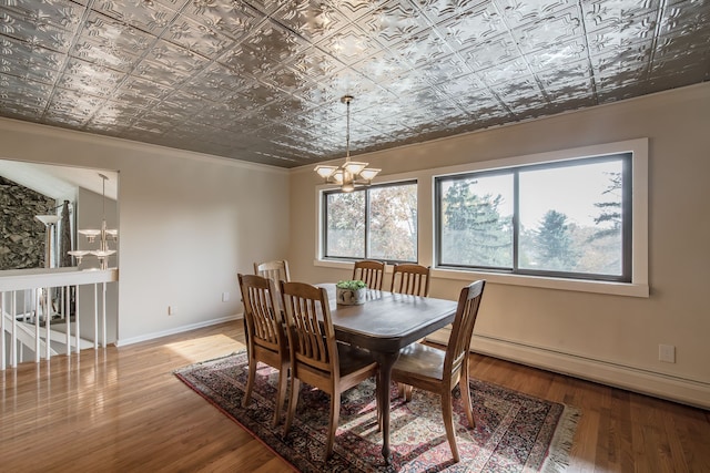 dining room with hardwood / wood-style flooring, a notable chandelier, baseboard heating, and crown molding