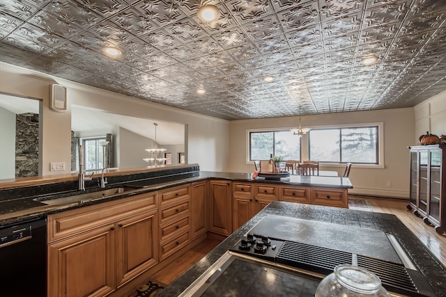 kitchen featuring light hardwood / wood-style floors, sink, pendant lighting, dishwasher, and a chandelier