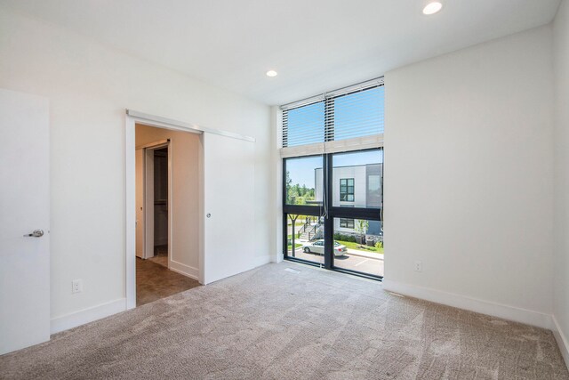 unfurnished room featuring plenty of natural light and light carpet