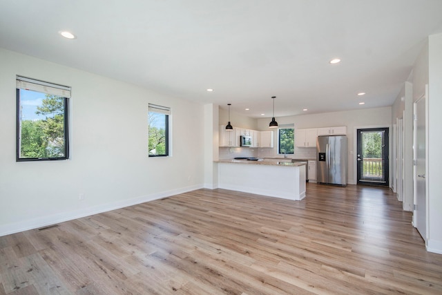 unfurnished living room with plenty of natural light and light hardwood / wood-style flooring