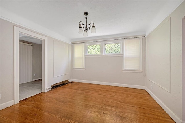 unfurnished room featuring an inviting chandelier and hardwood / wood-style flooring