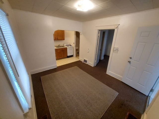 corridor with sink, plenty of natural light, dark colored carpet, and washer / dryer