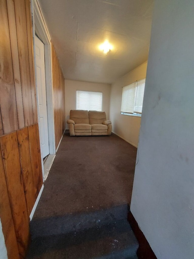 interior space featuring dark colored carpet and wooden walls