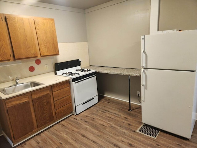kitchen with decorative backsplash, hardwood / wood-style floors, white appliances, and sink