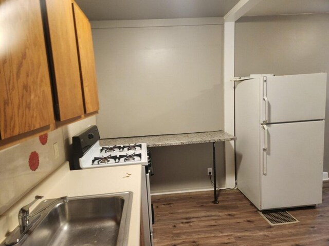 kitchen with white appliances, sink, and dark wood-type flooring
