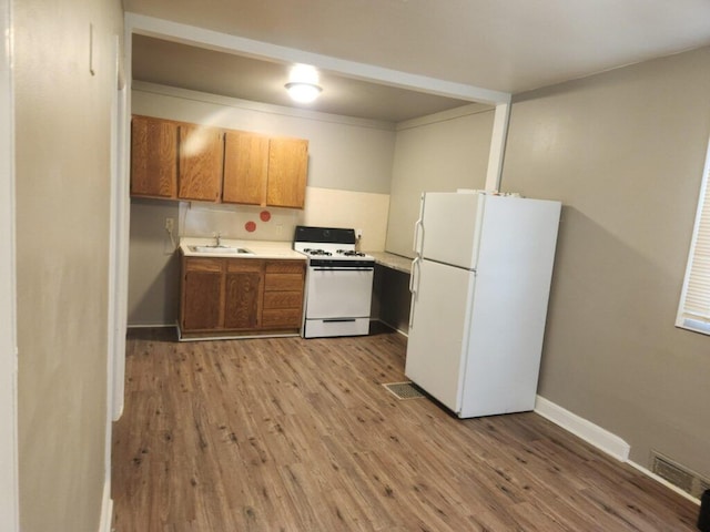 kitchen featuring white appliances, light hardwood / wood-style flooring, and sink