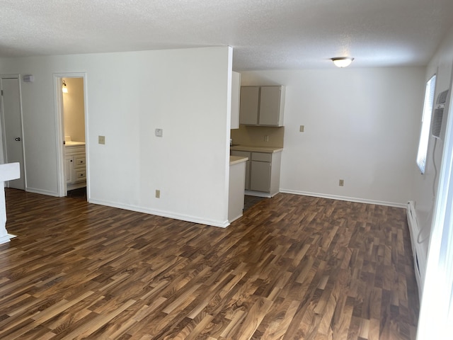 unfurnished living room featuring a textured ceiling, dark hardwood / wood-style flooring, and a baseboard radiator