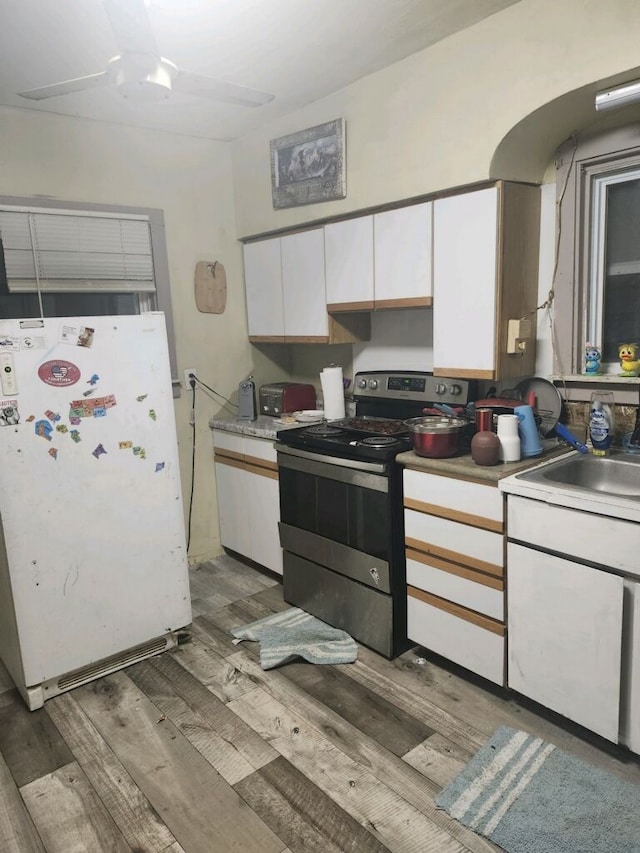 kitchen featuring electric range, white fridge, white cabinetry, and light hardwood / wood-style flooring