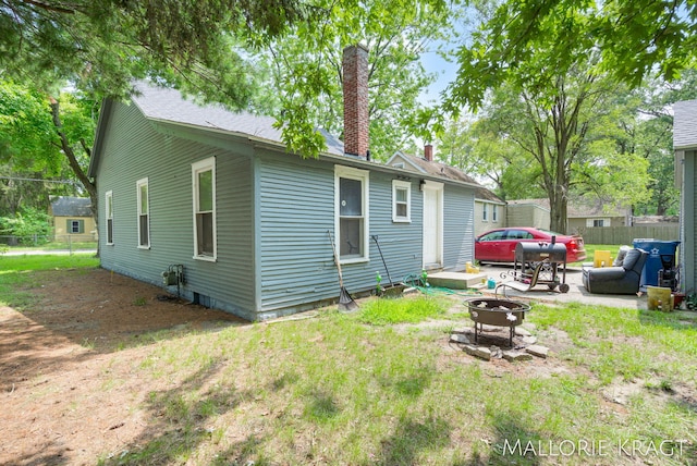 rear view of house featuring a yard and an outdoor fire pit