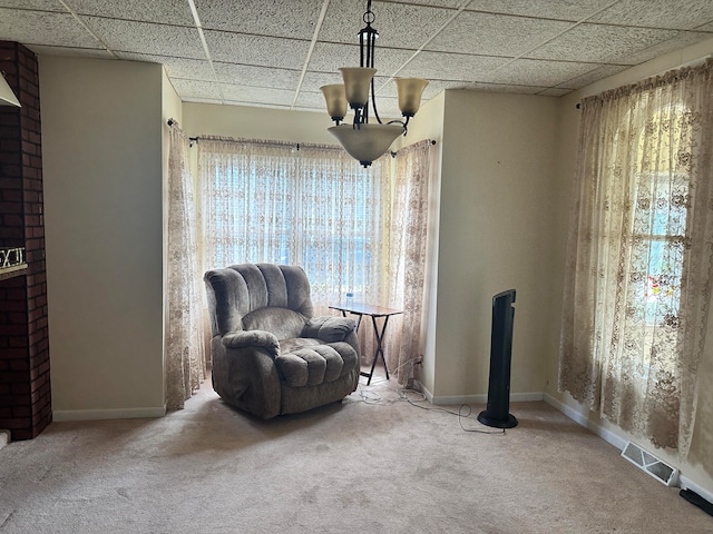 sitting room with carpet flooring, a paneled ceiling, and a chandelier