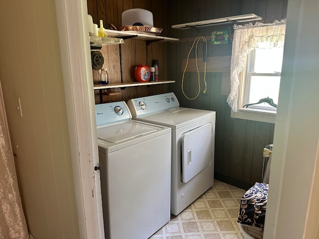 laundry area with washing machine and dryer and wooden walls