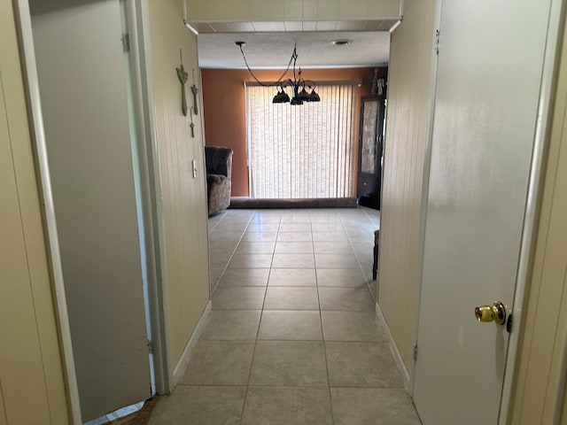 hall featuring light tile patterned floors and an inviting chandelier