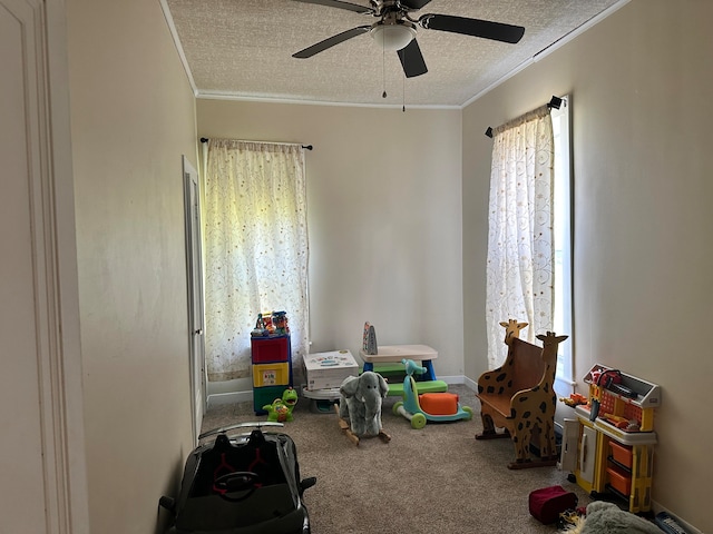 playroom featuring carpet flooring, ceiling fan, crown molding, and a textured ceiling