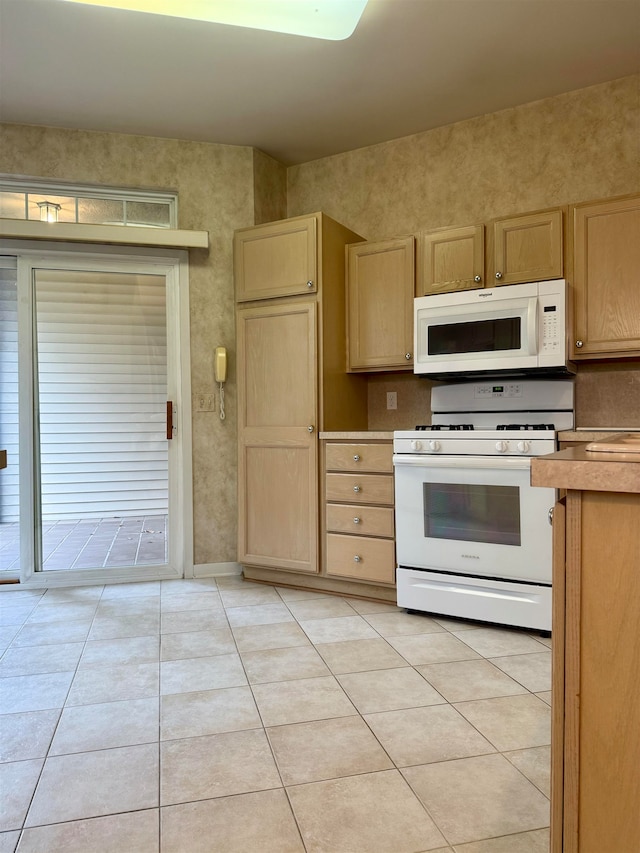 kitchen with light brown cabinetry, light tile patterned flooring, and white appliances