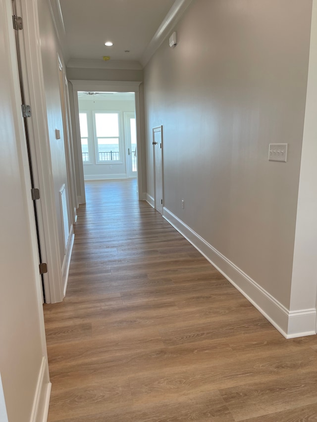 hallway with light hardwood / wood-style floors and crown molding