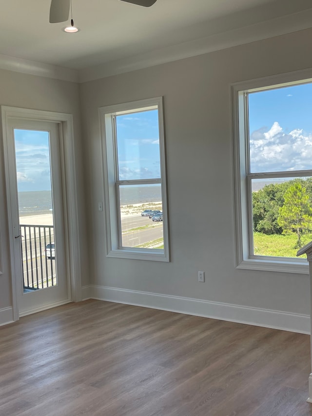 spare room featuring hardwood / wood-style flooring, ceiling fan, a water view, and crown molding