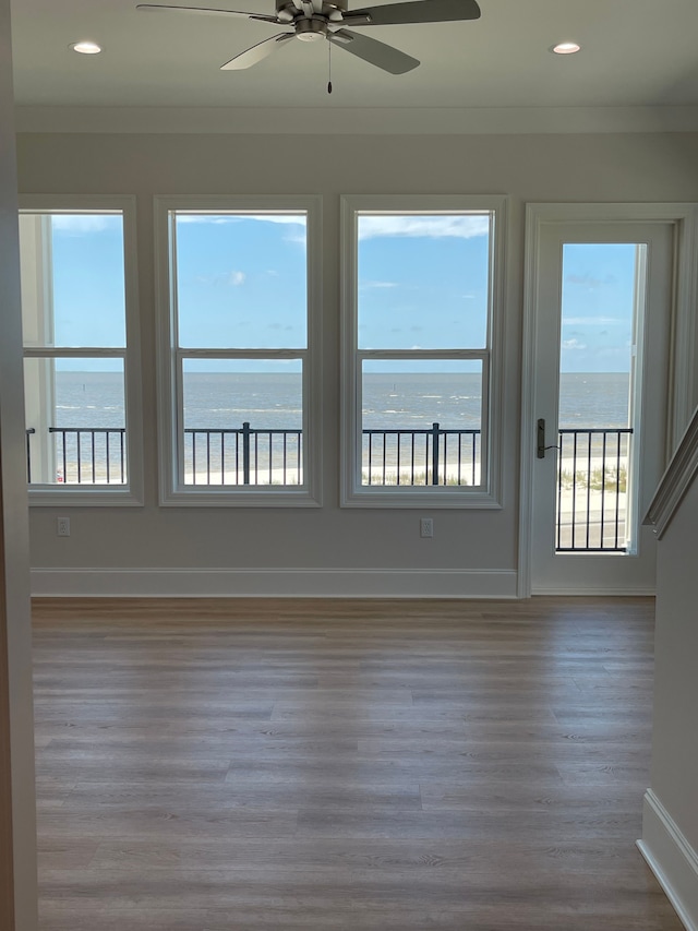 spare room featuring ceiling fan, a water view, and wood-type flooring