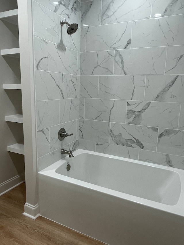 bathroom featuring tiled shower / bath combo, wood-type flooring, and built in shelves