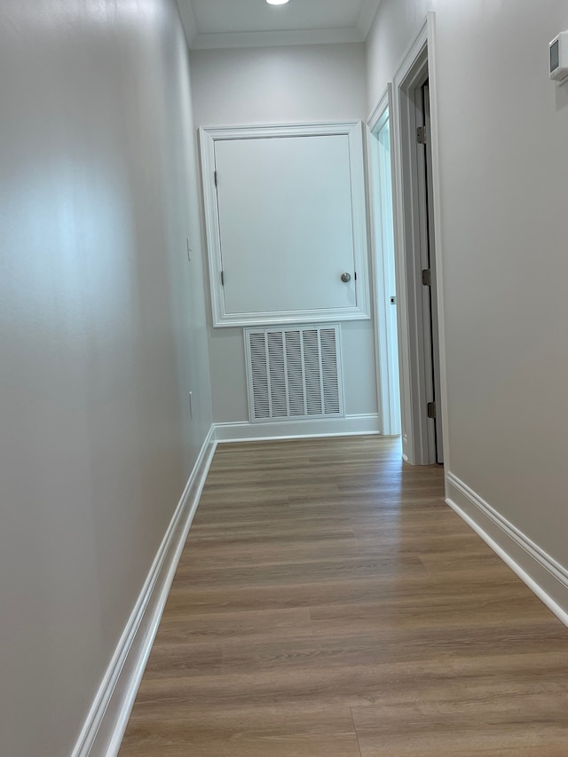 corridor with light wood-type flooring and crown molding