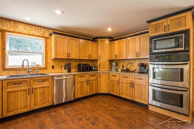 kitchen featuring sink, decorative backsplash, a textured ceiling, appliances with stainless steel finishes, and dark hardwood / wood-style flooring