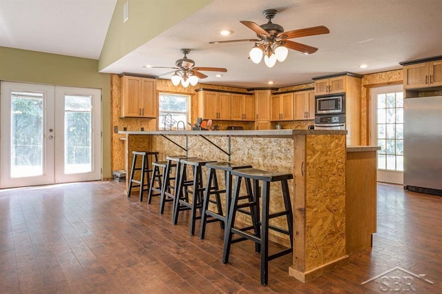 kitchen featuring a kitchen bar, french doors, stainless steel appliances, and dark hardwood / wood-style floors