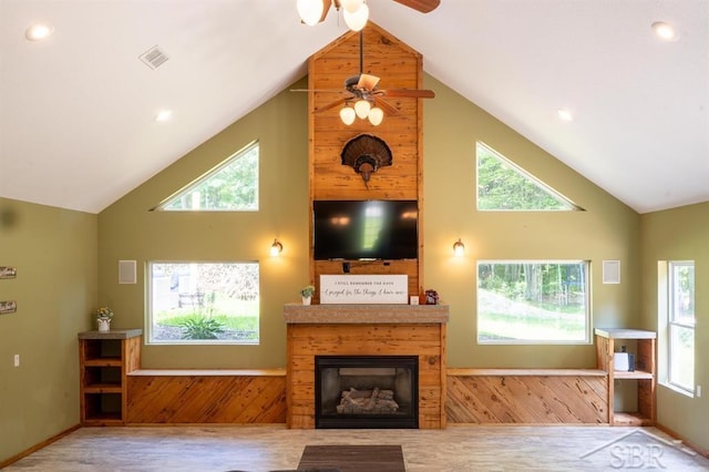 living room featuring hardwood / wood-style floors, ceiling fan, high vaulted ceiling, and wooden walls