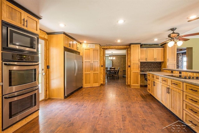 kitchen with decorative backsplash, dark wood-type flooring, stainless steel appliances, and ceiling fan with notable chandelier