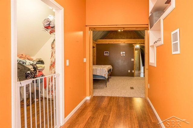 hall with hardwood / wood-style floors and vaulted ceiling with beams