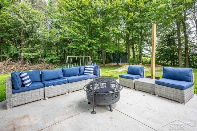 view of patio / terrace with a playground, a trampoline, and an outdoor living space with a fire pit