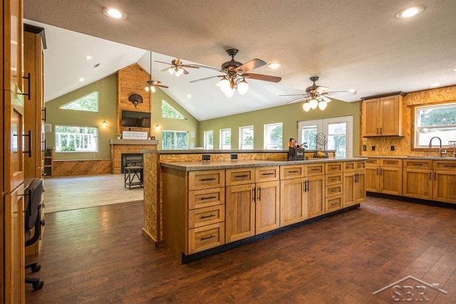 kitchen with a textured ceiling, a fireplace, dark wood-type flooring, and wooden walls