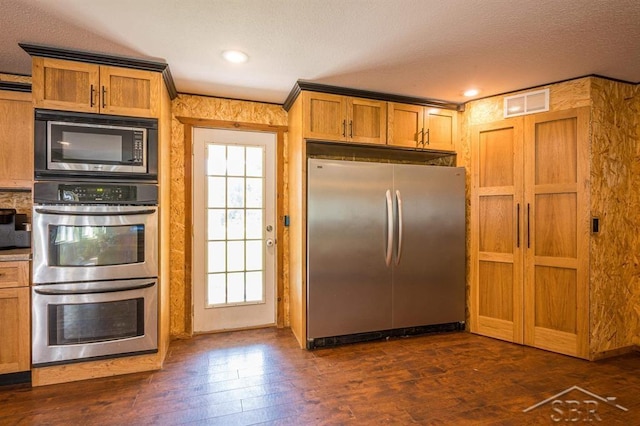 kitchen with appliances with stainless steel finishes, dark hardwood / wood-style flooring, a textured ceiling, and ornamental molding