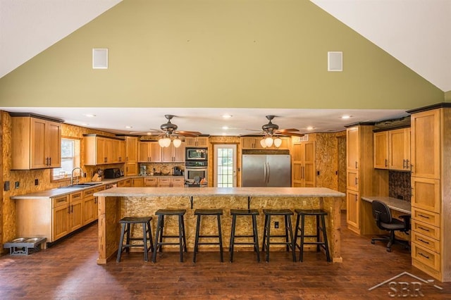 kitchen with a spacious island, a breakfast bar area, appliances with stainless steel finishes, and dark wood-type flooring