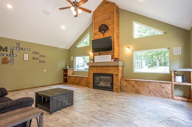 living room with a large fireplace, plenty of natural light, wood walls, and high vaulted ceiling