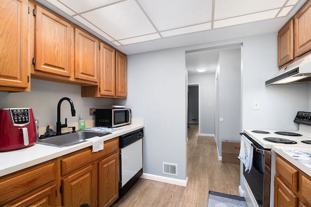 kitchen with a drop ceiling, light wood-type flooring, white appliances, and sink