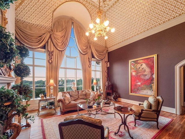 interior space with crown molding, hardwood / wood-style flooring, a towering ceiling, a notable chandelier, and a healthy amount of sunlight