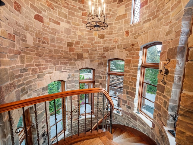 staircase with parquet flooring and a notable chandelier