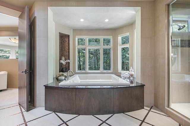 bathroom with tile patterned flooring, shower with separate bathtub, and tile walls