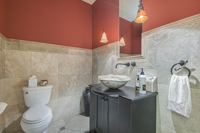 bathroom with vanity, toilet, and tile walls