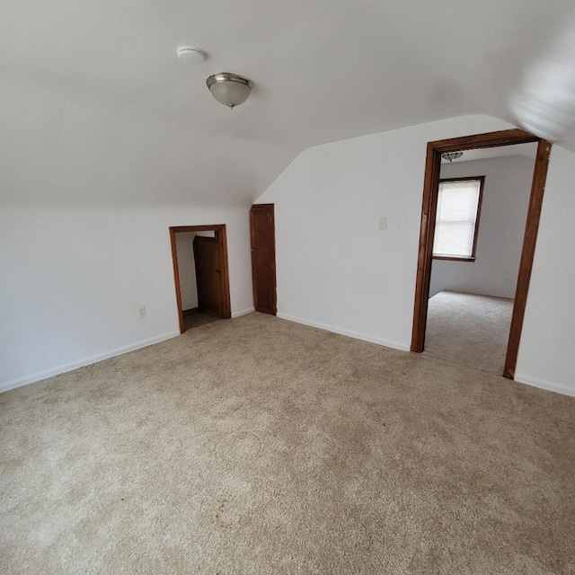 bonus room with light colored carpet and vaulted ceiling