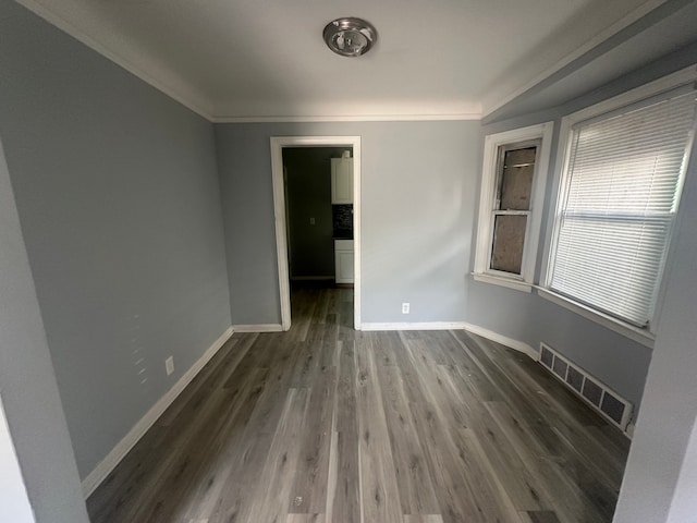 empty room featuring ornamental molding and dark wood-type flooring