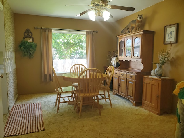 dining space with ceiling fan and light colored carpet