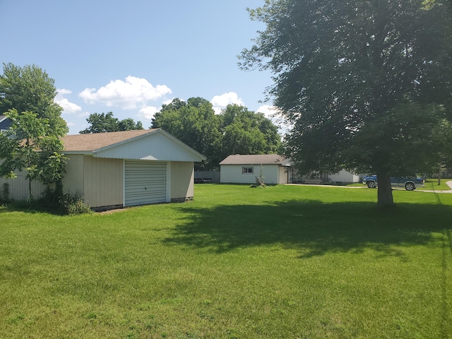 view of yard with a garage, driveway, and an outbuilding