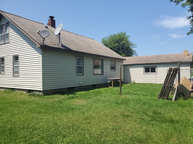 rear view of house with a chimney and a lawn