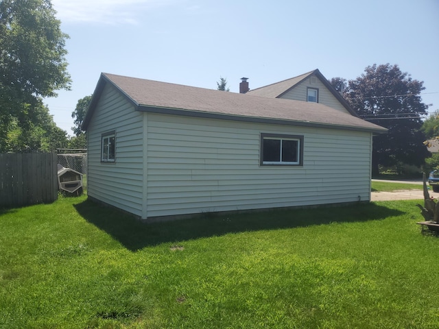 view of side of home featuring a lawn and fence