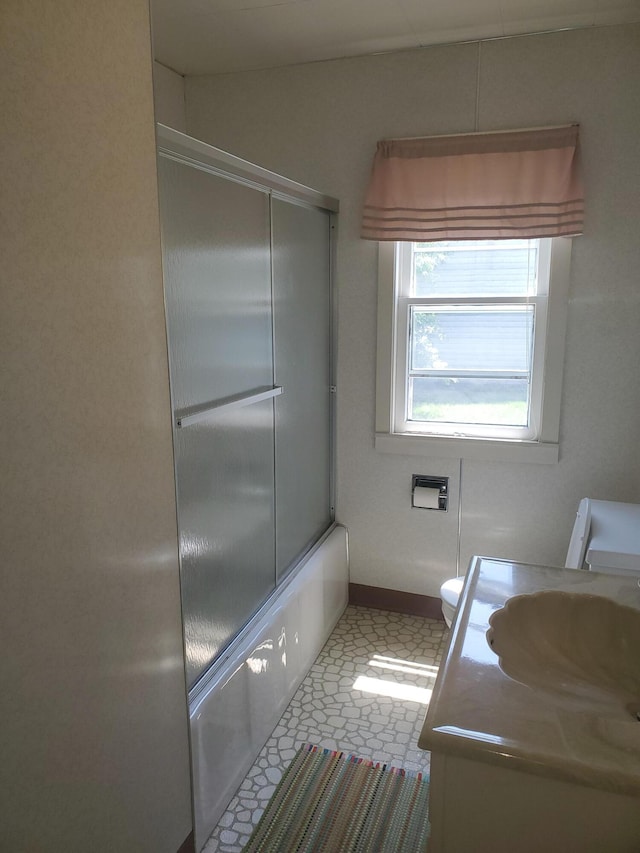 bathroom with shower / bath combination with glass door, vanity, toilet, and baseboards