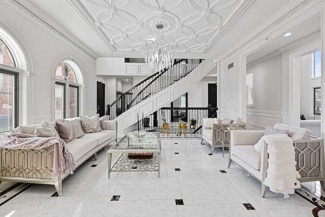 living room featuring plenty of natural light, ornamental molding, and a towering ceiling