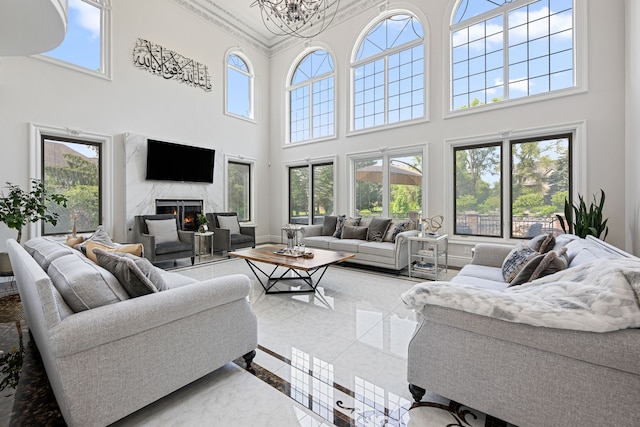 living room with a healthy amount of sunlight, a premium fireplace, and a towering ceiling