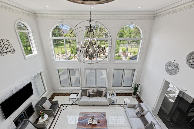 living room featuring a high ceiling, an inviting chandelier, a healthy amount of sunlight, and crown molding