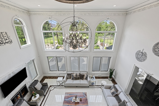 living room featuring plenty of natural light, a premium fireplace, crown molding, and a chandelier