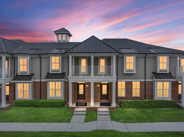 view of front of home featuring a lawn and a balcony